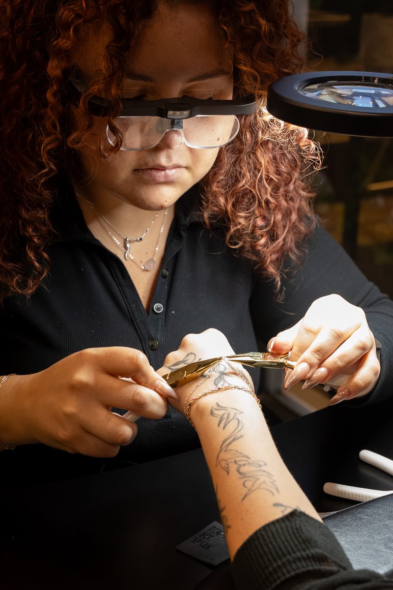 Stylist applying a gold permanent bracelet at Robert of Philadelphia